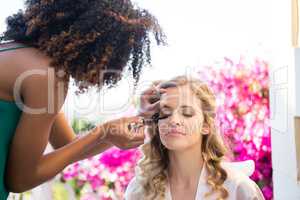 Side view of beautician applying mascara to bride