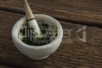 Herb paste in mortar and pestle on wooden table