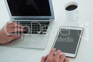 Cropped hands of businessman using laptop and tablet computer