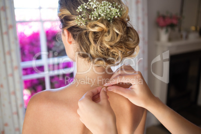 Bridesmaid fastening bride chain in dressing room