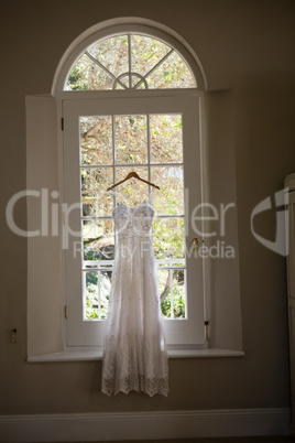 Wedding dress hanging on window in room