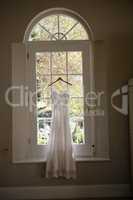 Wedding dress hanging on window in room