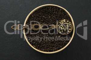 Black pepper and white pepper seeds in a bowl