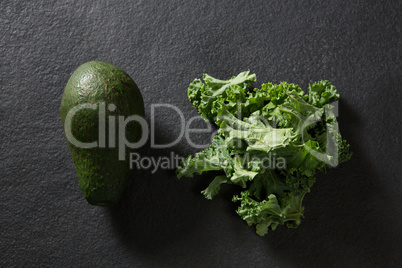 Avocado and mustard greens on black background