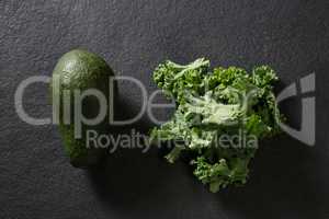 Avocado and mustard greens on black background