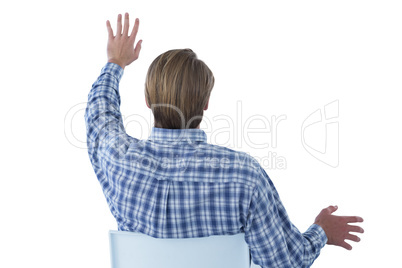 Rear view of businessman using imaginary interface while sitting on chair