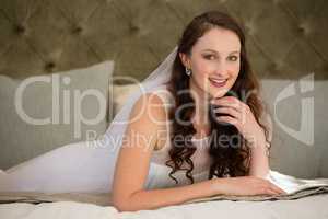 Portrait of beautiful bride in wedding dress lying on bed