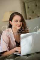 Beautiful bride using laptop while relaxing on bed at home