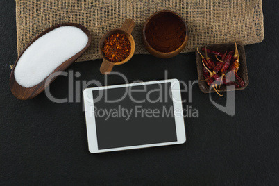 Various spices with digital tablet on black background