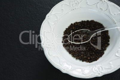 Black pepper in spoon and bowl