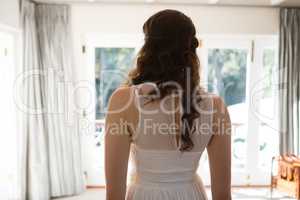 Bride in wedding dress standing at home