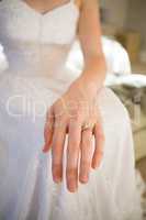 Midsection of bride showing wedding ring while sitting on bed