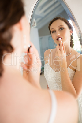 Rear view of beautiful bride applying lipstick reflecting on mirror