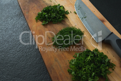Chopped herbs with knife on chopping board