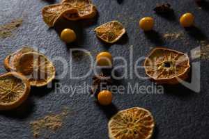 Dried orange with star anise and golden berries on black background