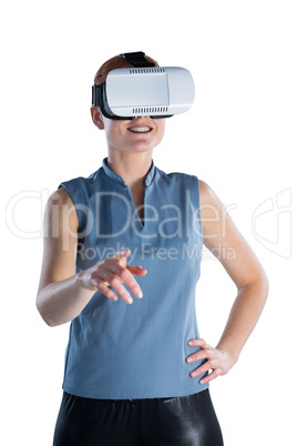 Smiling businesswoman with hand on hip gesturing while wearing virtual reality glasses