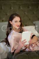 Portrait of beautiful bride using digital tablet while sitting on bed