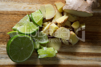 Chopped ginger and halved lemon on wooden board