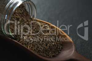 Cumin spilling out of jar into scoop