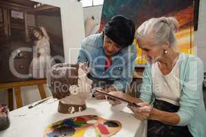 Woman using digital tablet while painting a sculptor