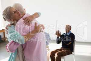 Happy senior friends applauding while looking at man and woman embracing