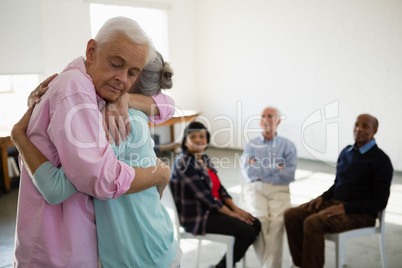 Senior friends looking at man and woman embracing