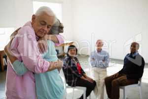 Senior friends looking at man and woman embracing