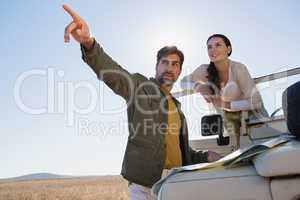 Man with woman pointing by off road vehicle