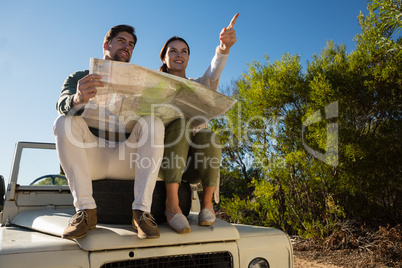 Woman with man pointing on off road vehicle with tire