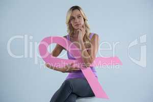 Thoughtful woman with Breast Cancer Awareness ribbon