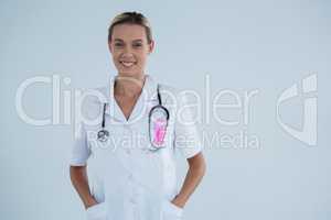 Portrait of smiling female doctor with Breast Cancer Awareness ribbon