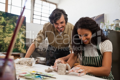 Man assisting woman in molding clay