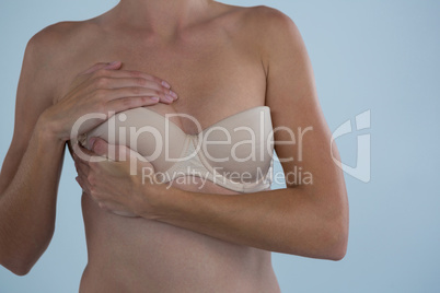 Mid section of young woman checking lumps while touching breast