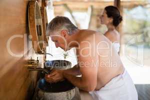 Man washing face from water in cottage