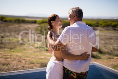 Smiling couple embracing near poolside