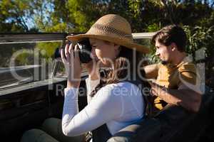 Woman photographing with man driving off road vehicle