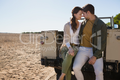 Romantic couple sitting in off road vehicle at landscape