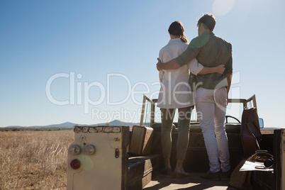 Rear view of couple with arms around on off road vehicle at landscape