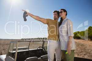 Man with woman pointing while standing on vehicle during sunny day