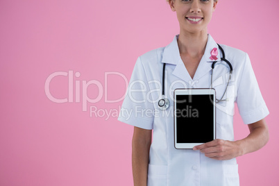 Mid section of smiling female doctor showing tablet computer