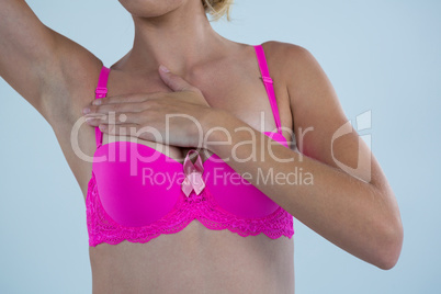 Mid section of woman in bra with Breast Cancer Awareness ribbon