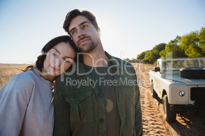 Couple standing by off road vehicle on field