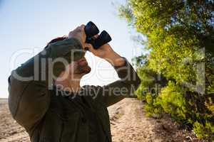 Man looking through binocular on field