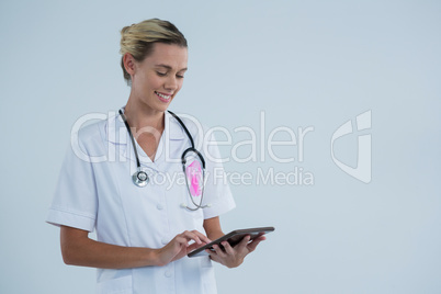 Smiling female doctor with Breast Cancer Awareness ribbon using tablet computer Smiling female doctor with Breast Cancer Awareness ribbon using tablet computer