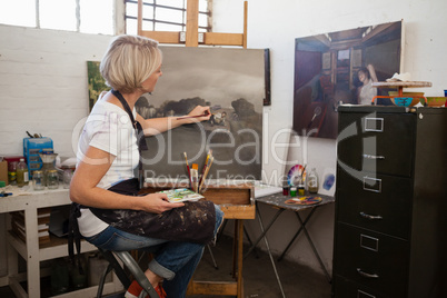 Woman painting on canvas in drawing class