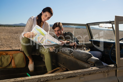 Young couple reading map in off road vehicle