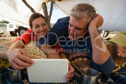 Man with woman looking at tablet in tent