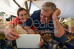 Man with woman looking at tablet in tent
