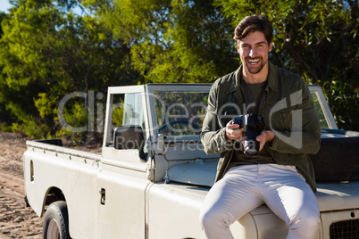 Portrait of man with camera on vehicle hood