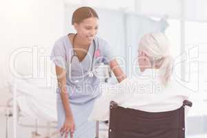 Composite image of smiling nurse assisting female patient in wheelchair